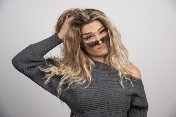 Mulher analisando seu contraste de tons de pele, cabelo e olhos antes de optar por um tom loiro de cabelo.