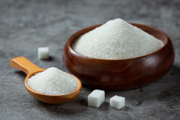 Imagem ilustrando uma balança e alimentos saudáveis, simbolizando a perda de peso ao reduzir o consumo de açúcar.