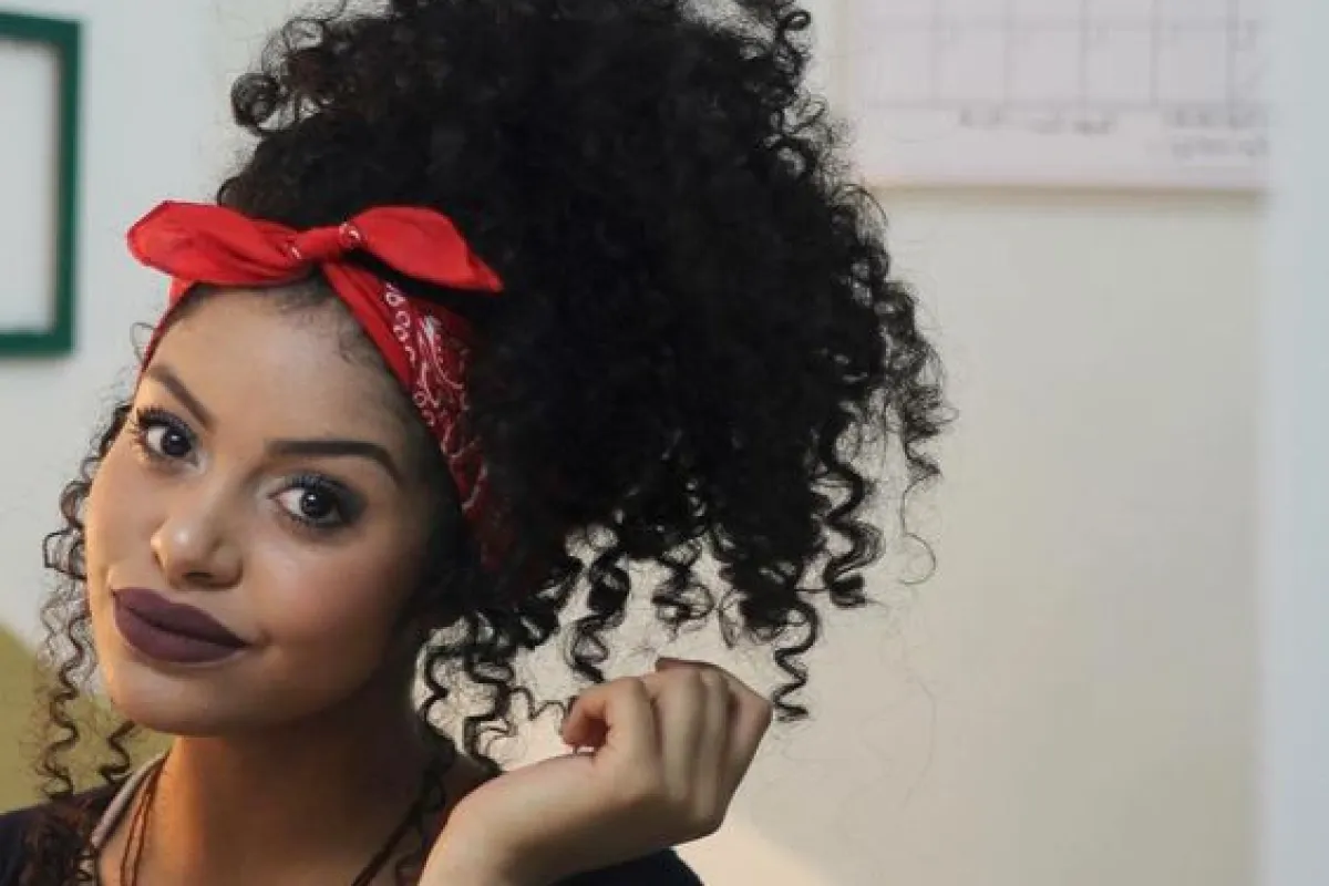 Cabelo cacheado estilizado com uma bandana colorida, adicionando um toque de cor e estilo ao penteado natural.