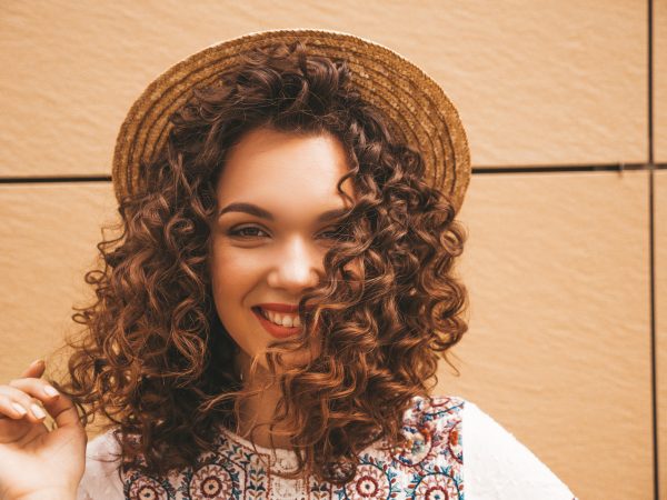 Cabelos Cacheados: Mulher sorridente exibindo seu novo corte de cabelo cacheado, um estilo moderno e elegante que realça a beleza natural dos cachos.