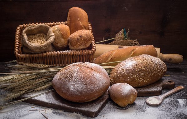 Variedade de pães em uma mesa, representando a discussão sobre "Pão engorda a barriga?" e enfatizando escolhas alimentares saudáveis.