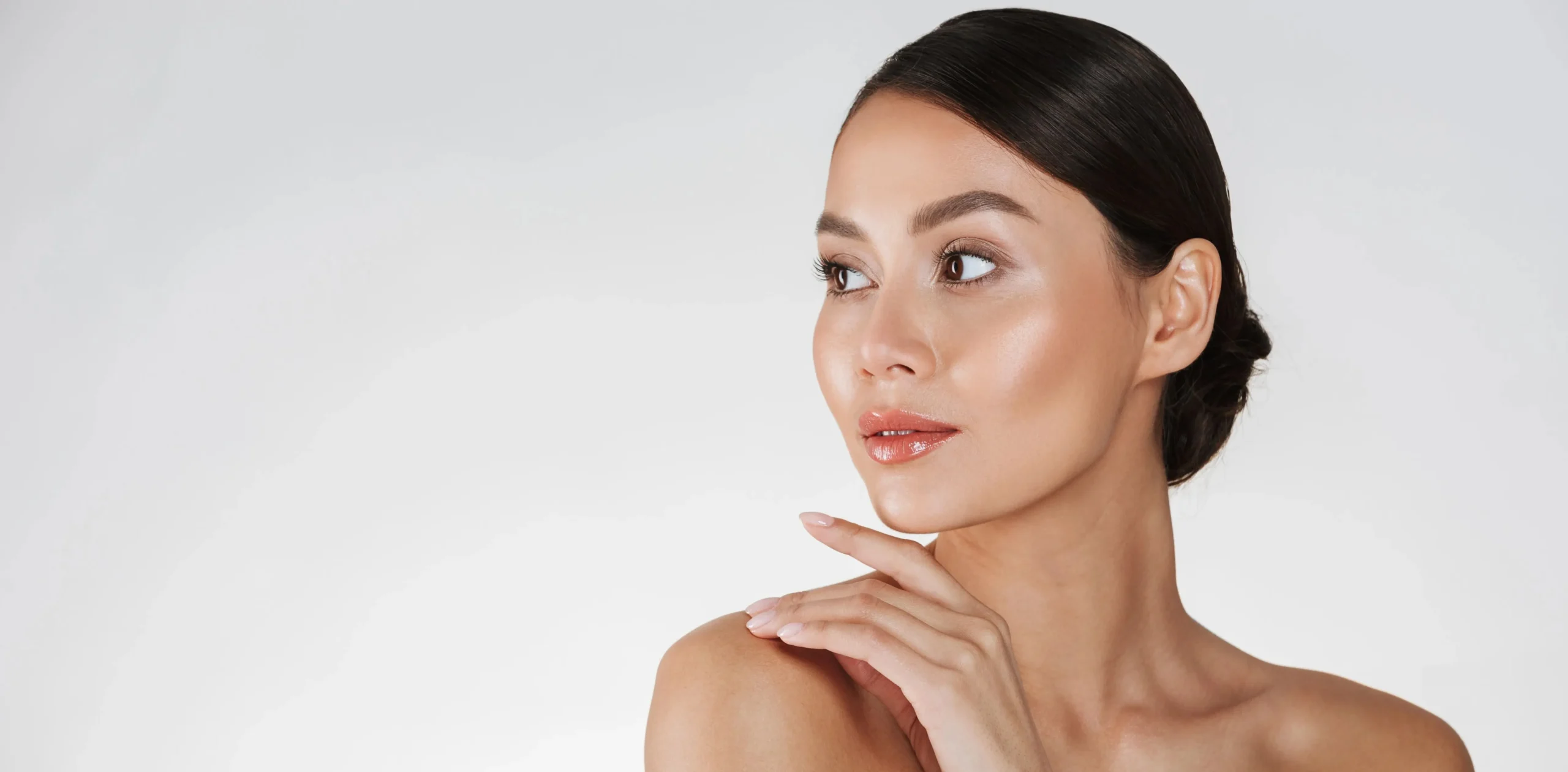 Mulher com pele radiante olhando para o lado, representando cuidados com a pele e rejuvenescimento.